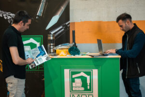 Equipa da IMOP atendendo visitantes e mostrando catálogos de componentes para máquinas de construção no seu stand durante o evento em Granada.