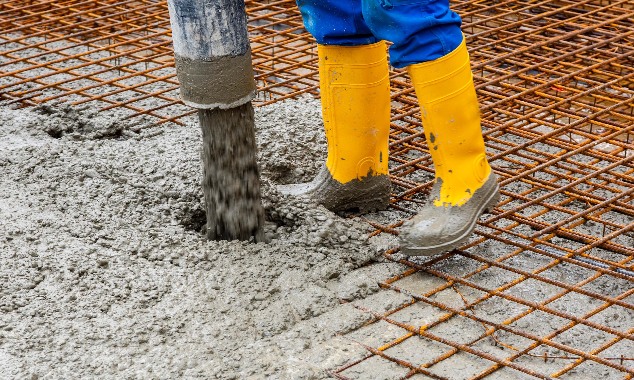 Pouring reinforced concrete over wire mesh for the foundation of a modular home.