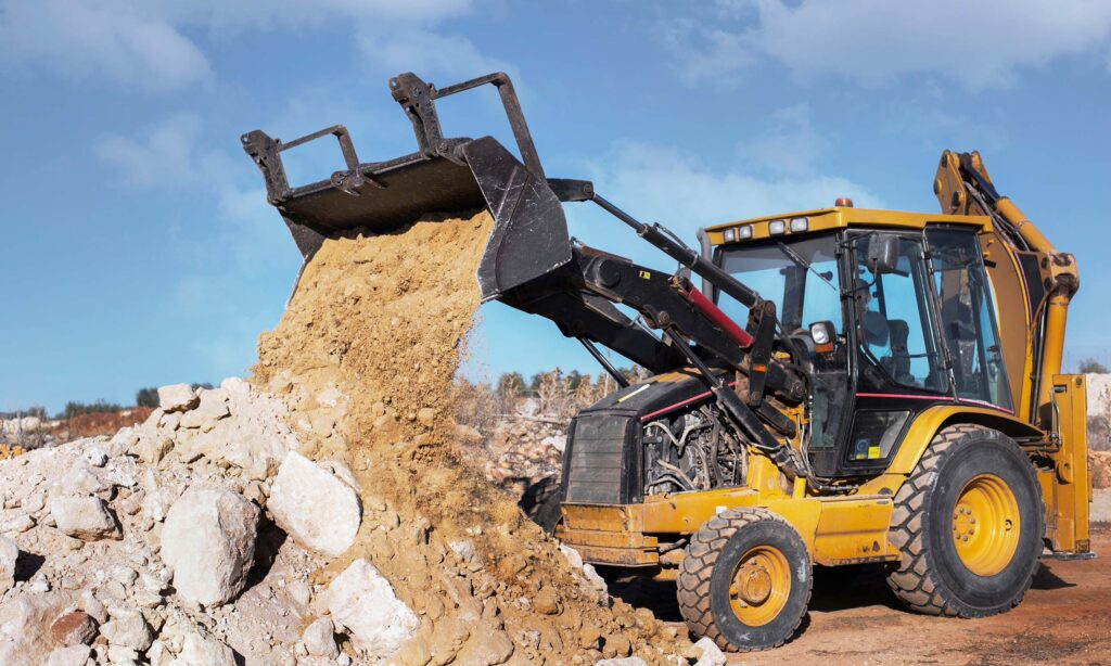Pala cargadora en obra cargando material con cucharón frontal durante trabajos de construcción