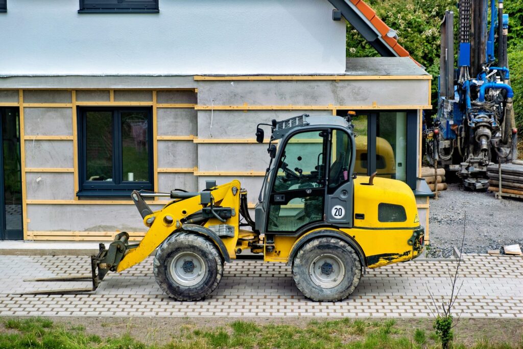 Compact skid steer loader performing material handling tasks at a construction site.